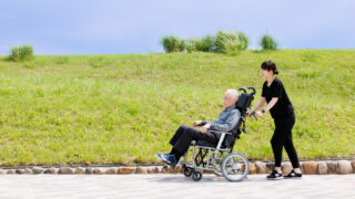 車いすの方と付き添うスタッフが屋外を進む様子